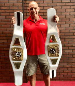Eric Stehle holding belts at his kickboxing business