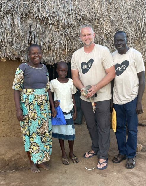 Part of the Shine story, showing a Shine team member with a family in Uganda through Arrows + Hope, reflecting Shine’s commitment to service, community impact, and purpose-driven work.