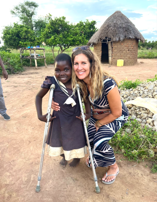 Shine founder Michelle Fisher with a child supported through Arrows + Hope in Uganda, reflecting Shine’s commitment to community impact and purpose-driven service.