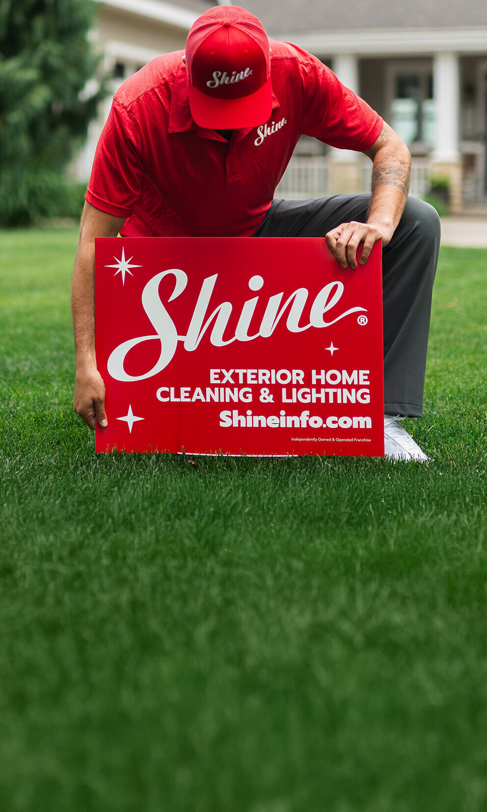 Shine Franchise technician with a red yard sign providing professional window cleaning services at a residential property.