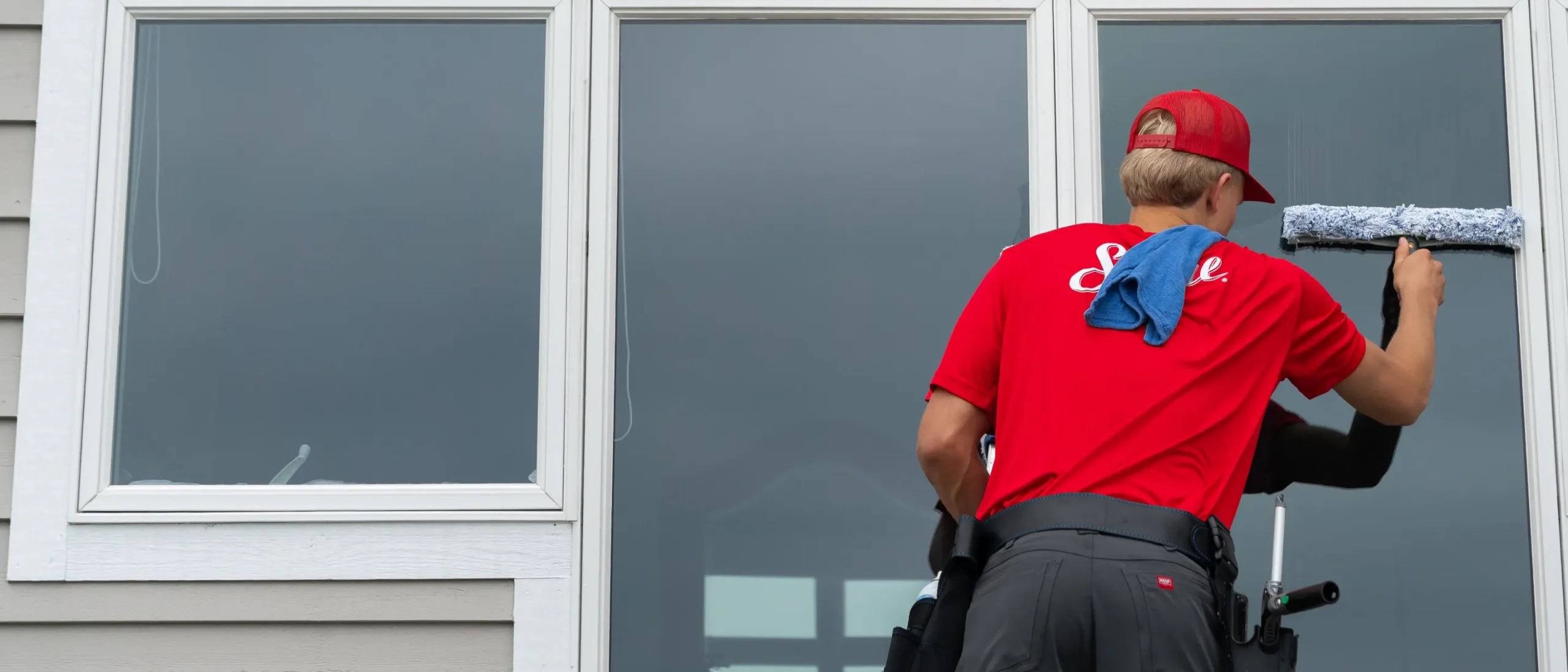 Shine Franchise technician providing professional window cleaning services at a residential property.