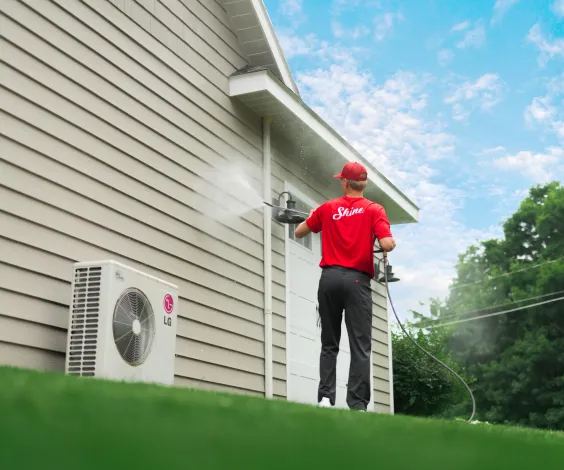 Shine technician pressure washing the exterior of a residential home