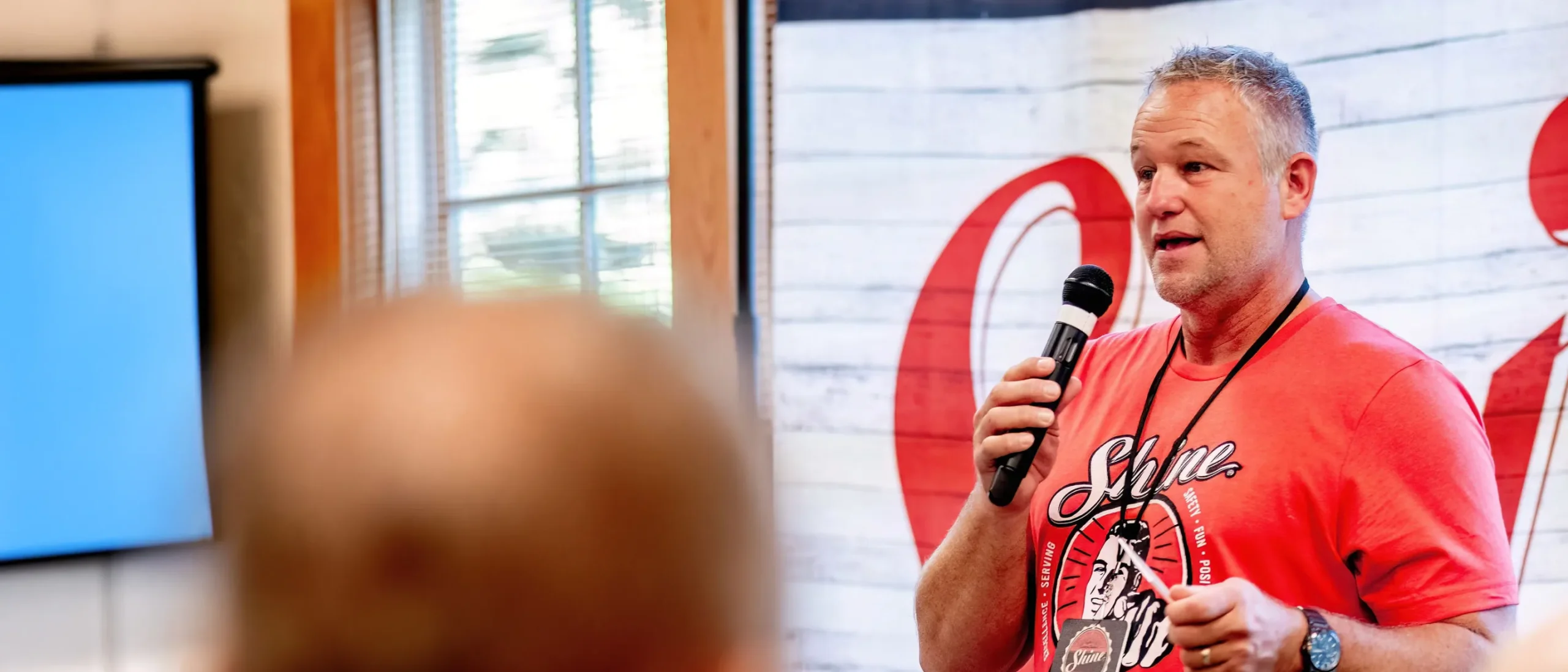 Shine Franchise leader speaking at a team meeting with a microphone